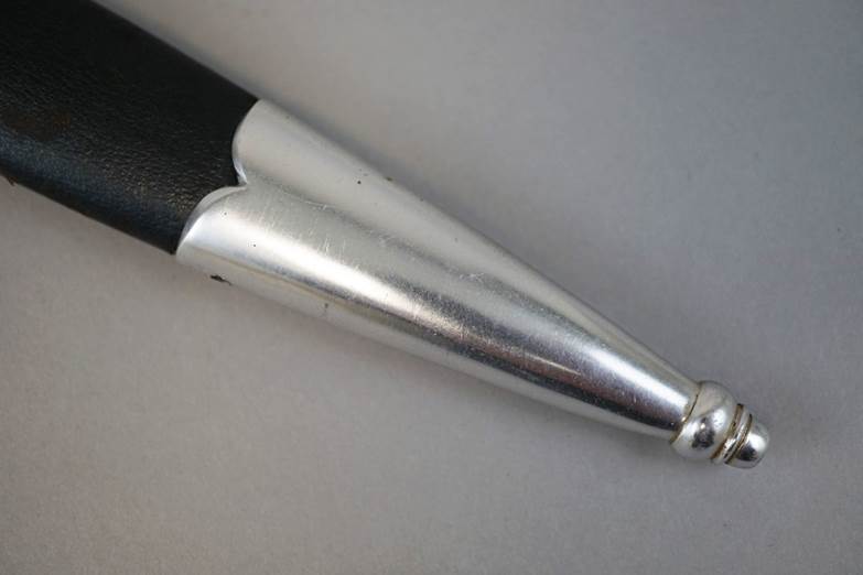 A silver pen on a white surface

Description automatically generated with low confidence