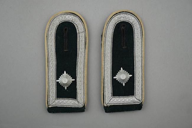 A pair of black and white military uniform shoulder pads

Description automatically generated