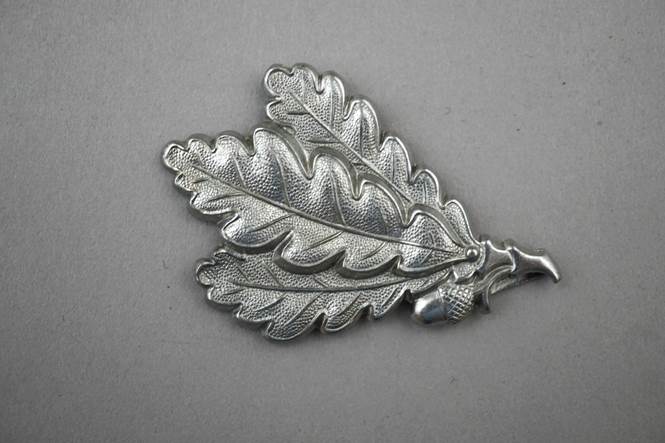 A silver leaf shaped object

Description automatically generated