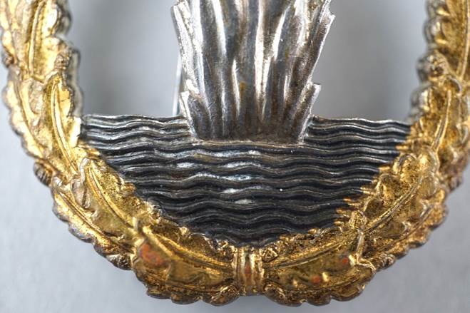 A close-up of a gold and silver brooch

Description automatically generated