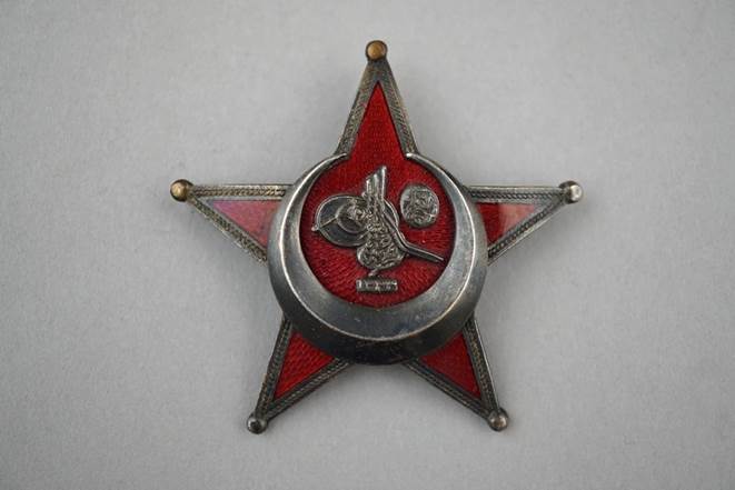 A red star with a crescent moon on it

Description automatically generated