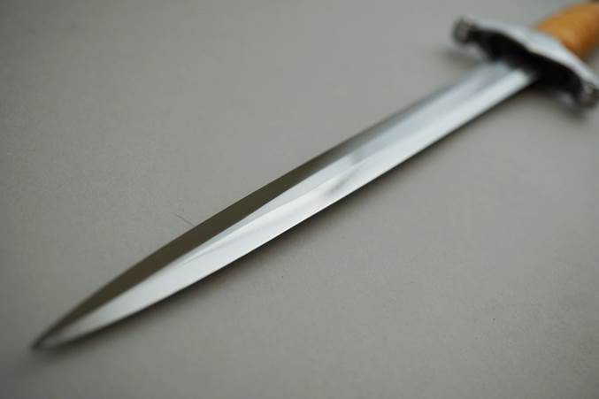 A long sword on a white surface

Description automatically generated