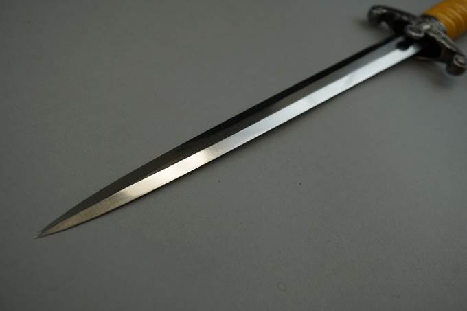 A sword on a white surface

Description automatically generated