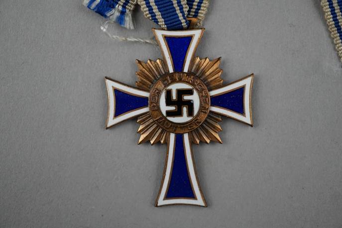 A gold cross with a blue and white ribbon

Description automatically generated