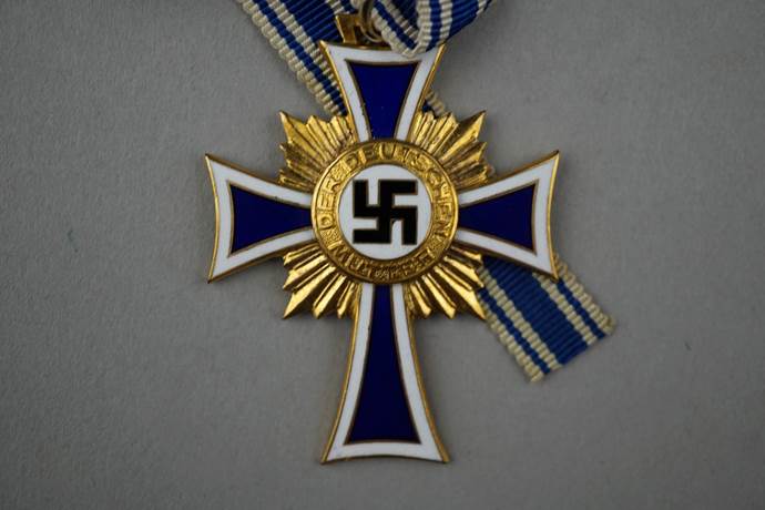 A gold and blue cross with a swastika

Description automatically generated