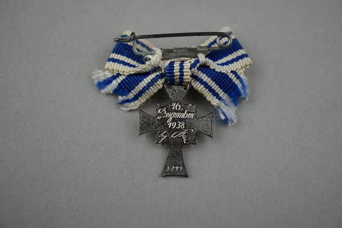 A pin with a blue and white ribbon

Description automatically generated