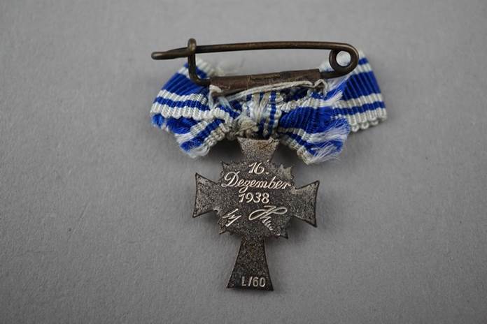 A pin with a blue and white ribbon

Description automatically generated