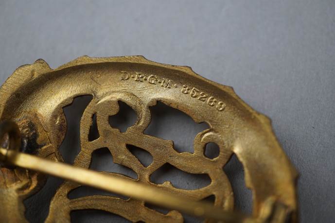 A close-up of a gold brooch

Description automatically generated