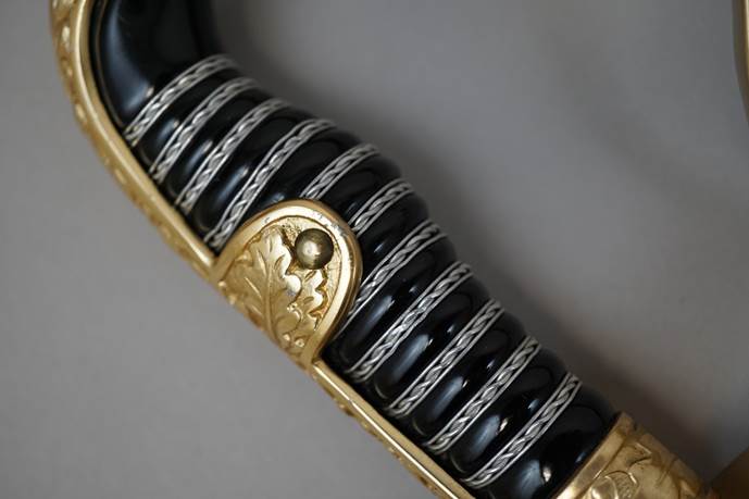 Close-up of a black and gold knife handle

Description automatically generated