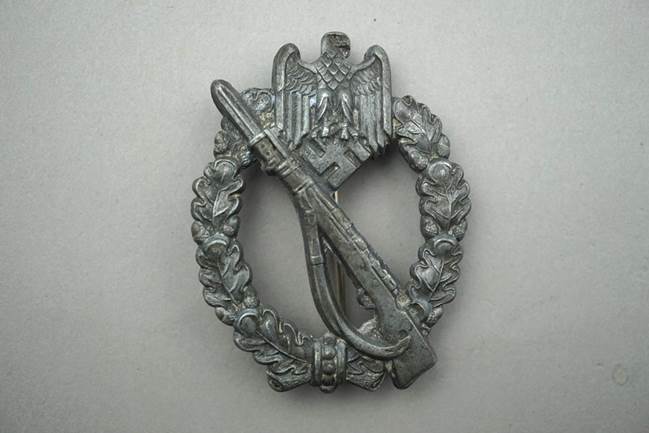A metal badge with an object and a wreath

Description automatically generated