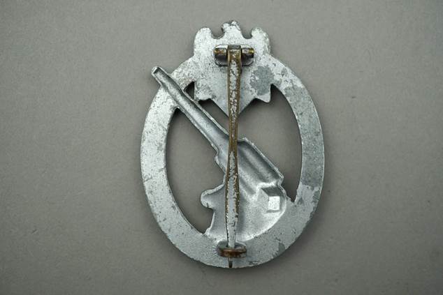 A metal badge with an object and a stick

Description automatically generated with medium confidence