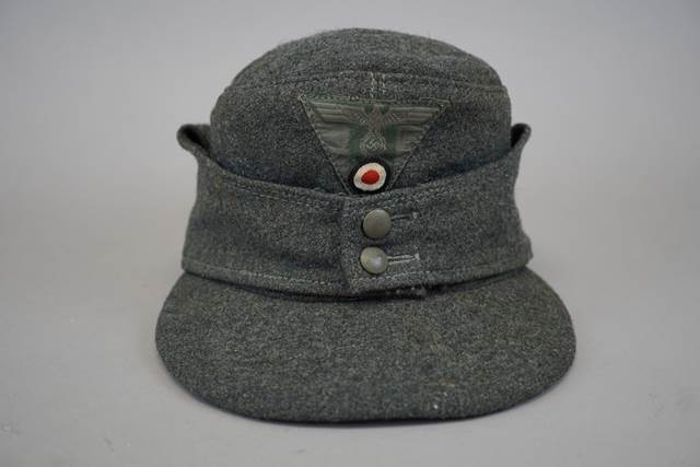 A grey hat with a red and white button

Description automatically generated