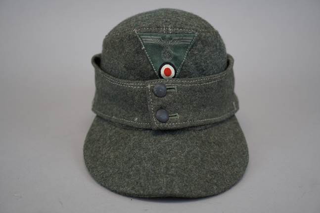 A green hat with a red and white patch

Description automatically generated