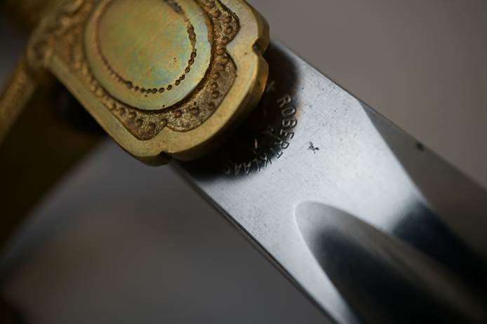 Close-up of a knife with a brass handle

Description automatically generated