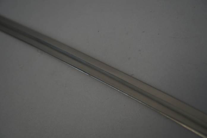A long metal sword on a white surface

Description automatically generated