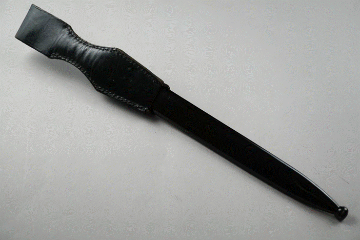 A black knife with a leather sheath

Description automatically generated