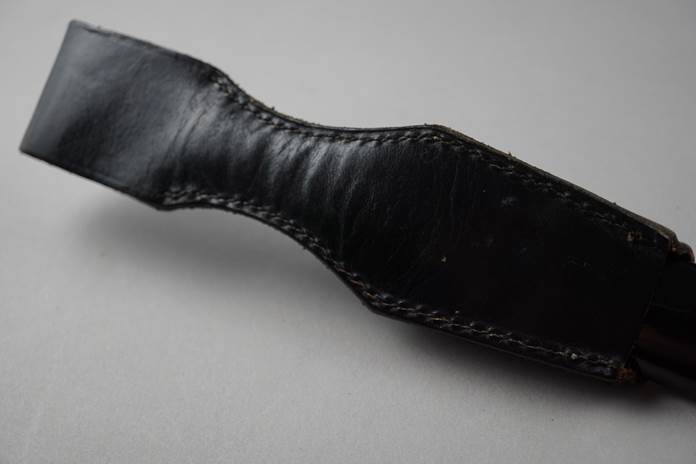 A black leather strap with stitching

Description automatically generated