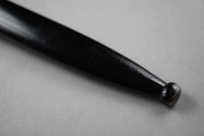 A close-up of a black ball point pen

Description automatically generated