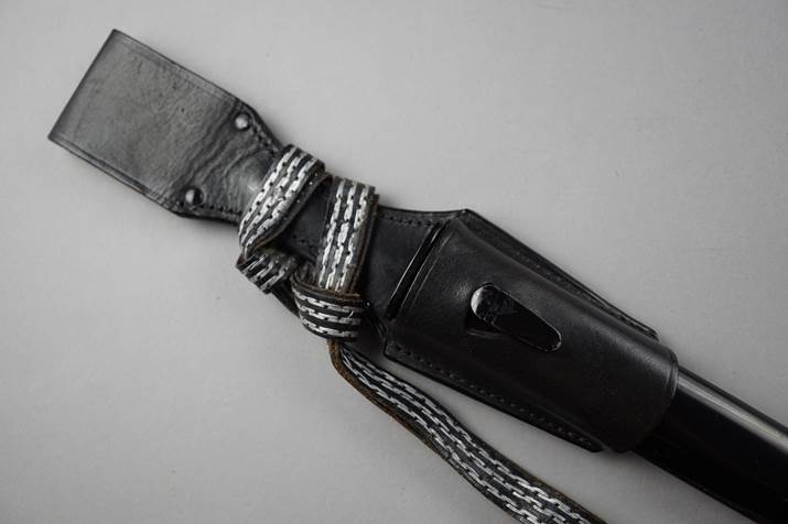 A black leather sheath with a black and white strap

Description automatically generated