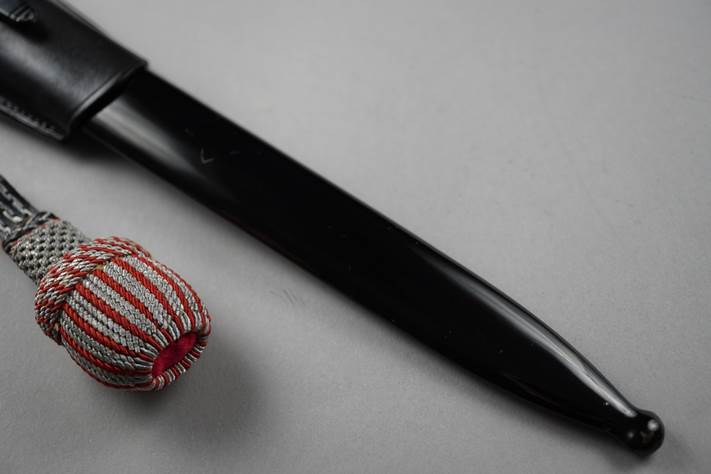 A black knife with a black handle next to a red and white striped object

Description automatically generated
