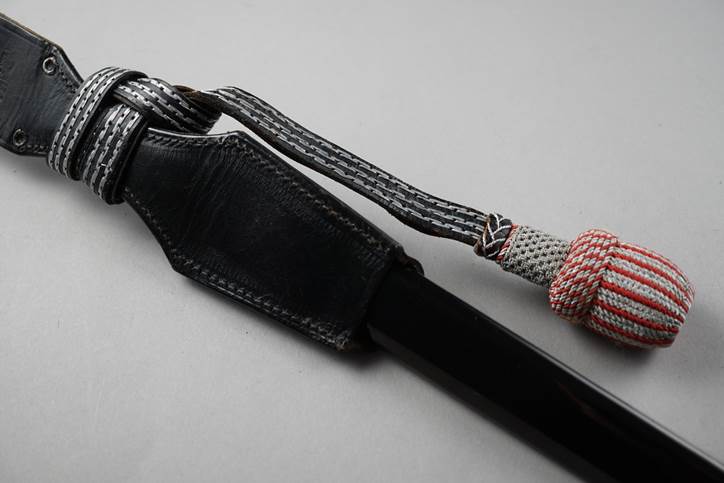 A black and silver sword with a strap

Description automatically generated