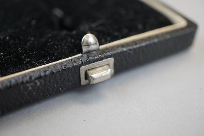 Close-up of a black case with a silver clasp

Description automatically generated