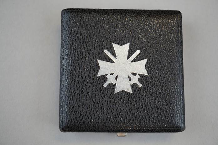 A black leather case with a silver cross on it

Description automatically generated