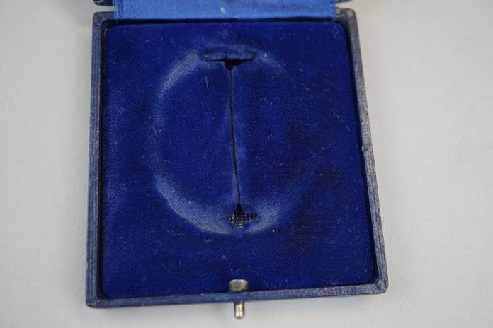 A blue velvet box with a hole in it

Description automatically generated