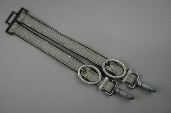 A pair of grey straps with metal rings

Description automatically generated