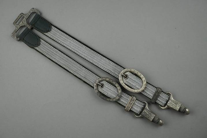 A pair of silver straps with buckles

Description automatically generated