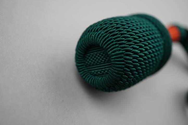 A green knitted object on a white surface

Description automatically generated