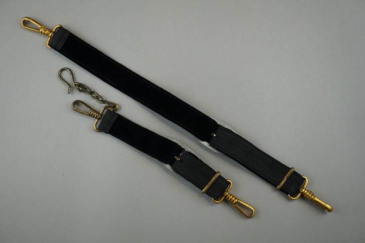 A pair of black straps with gold clasps

Description automatically generated