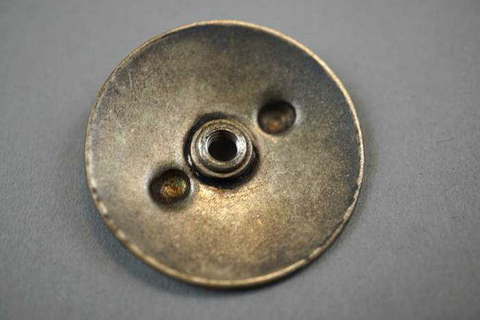 A close-up of a metal button

Description automatically generated