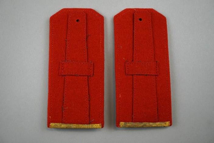 A pair of red felt shoulder straps

Description automatically generated