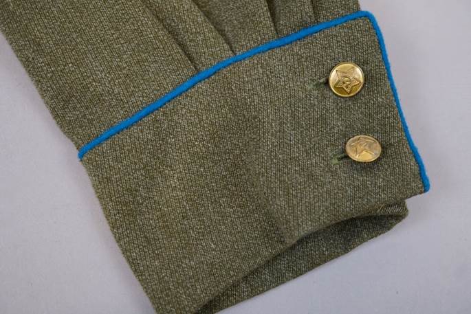 A close-up of a green uniform sleeve

Description automatically generated