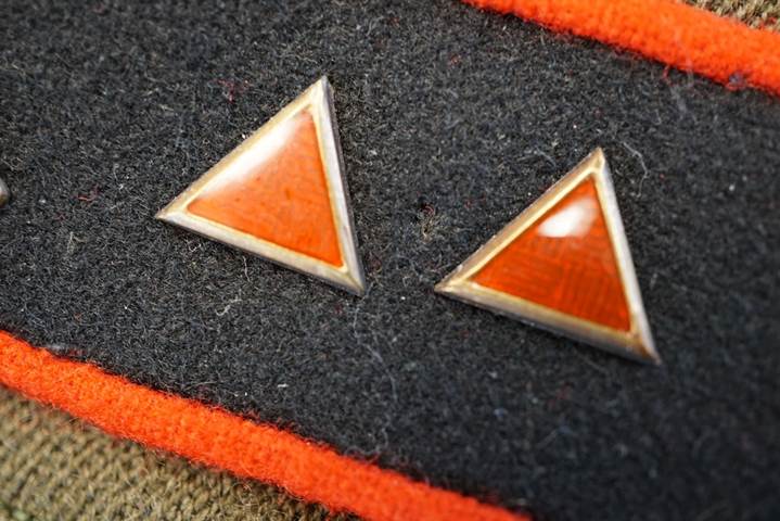 A pair of orange triangle buttons on a black and orange fabric

Description automatically generated