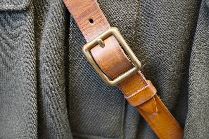 A brown leather strap on a person's jacket

Description automatically generated