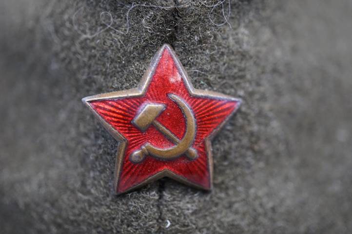 A red star with a hammer and sickle on a grey felt hat

Description automatically generated