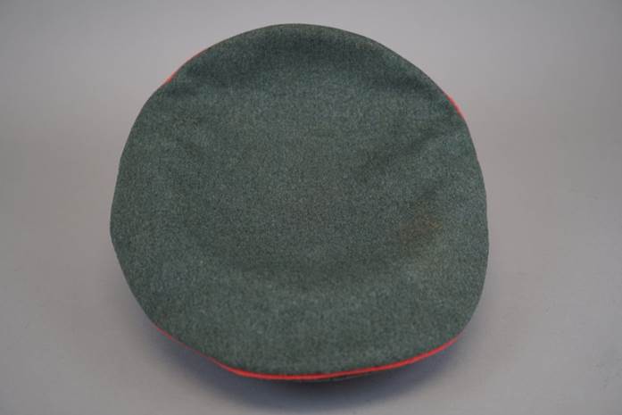 A green hat with red trim

Description automatically generated
