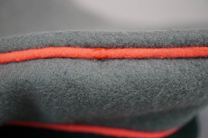 Close-up of a grey hat with a red stripe

Description automatically generated