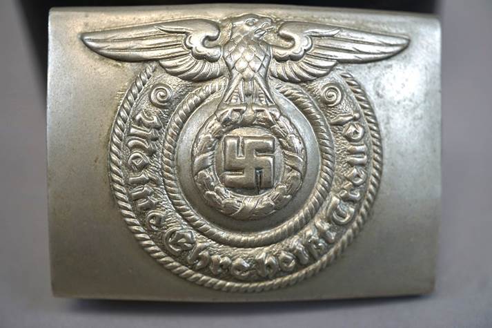 A silver belt buckle with a symbol

Description automatically generated