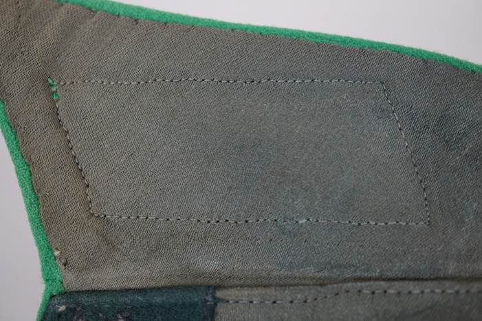 A close-up of a patch on a green fabric

Description automatically generated