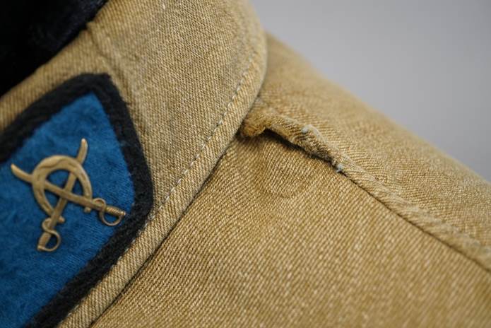 Close-up of a blue and black patch on a tan shirt

Description automatically generated