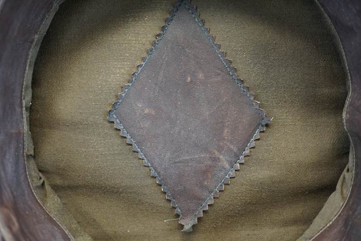 A diamond shaped leather patch on a green fabric

Description automatically generated
