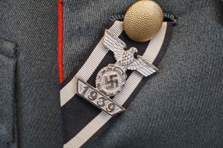 A military uniform with a pin and a badge

Description automatically generated