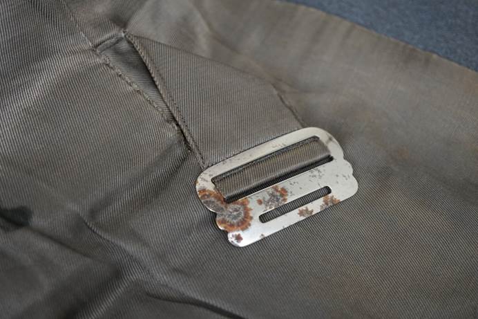 A metal buckle on a piece of fabric

Description automatically generated