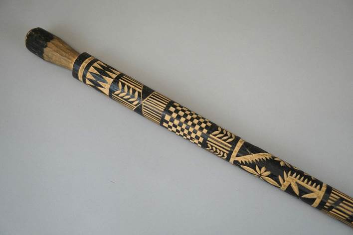 A long wooden stick with a design on it

Description automatically generated