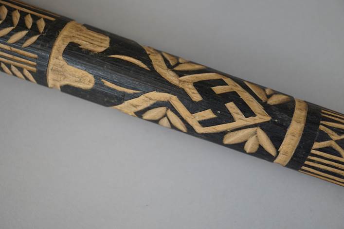 A close-up of a carved wooden stick

Description automatically generated