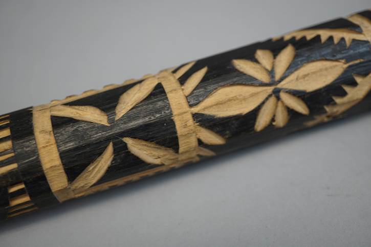 A close-up of a carved wooden stick

Description automatically generated