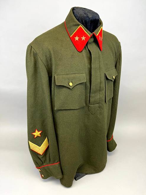 A green uniform with red and gold patches

Description automatically generated